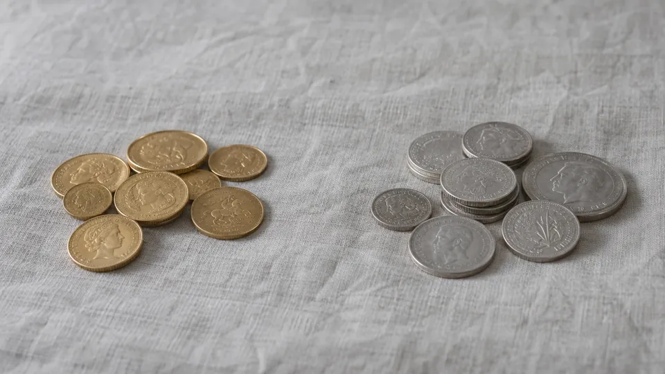 Gold coins and silver coins in two groups on grey linen